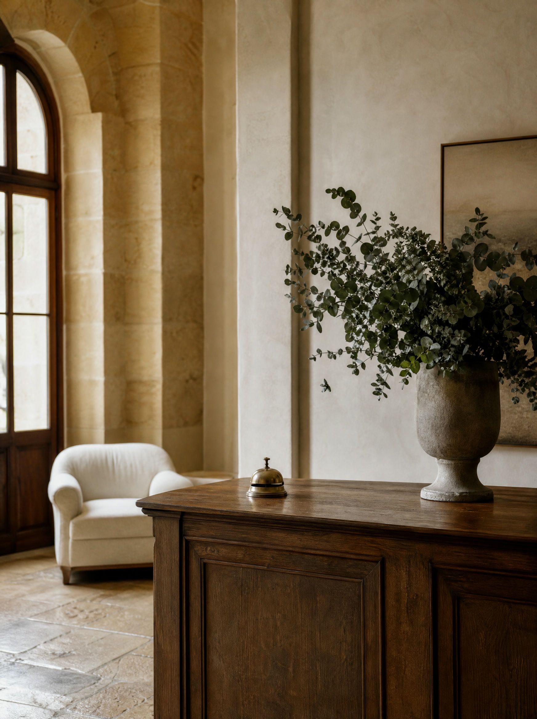 A boutique hotel lobby with an oak reception desk, a brass bell and morning light